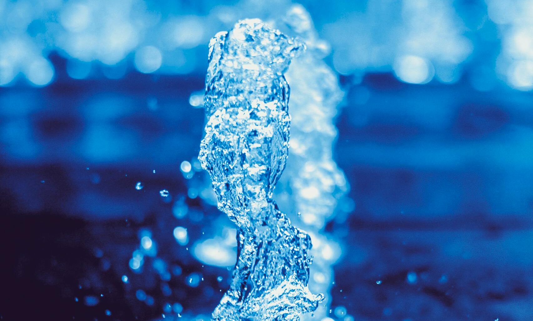 A dynamic close-up of a water fountain splash captured in vivid blue tones, showcasing motion and liquid beauty.